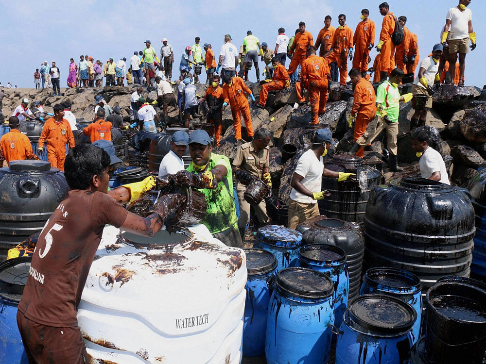 Coast Guard, State revenue personnel, local volunteers, and fishermen removing black oil washed ashore as a thick oily tide from the sea lapped at the coast on Thursday, a day after an oil tanker and an LPG tanker collided near Kamarajar Port in Ennore in Chennai. PTI Photo