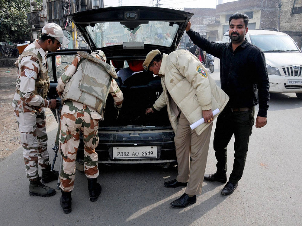 Paramilitary soldiers and a Punjab police officer check a vehicle in wake of heightened security on the eve of Punjab Assembly Elections, in Amritsar on Friday. PTI Photo