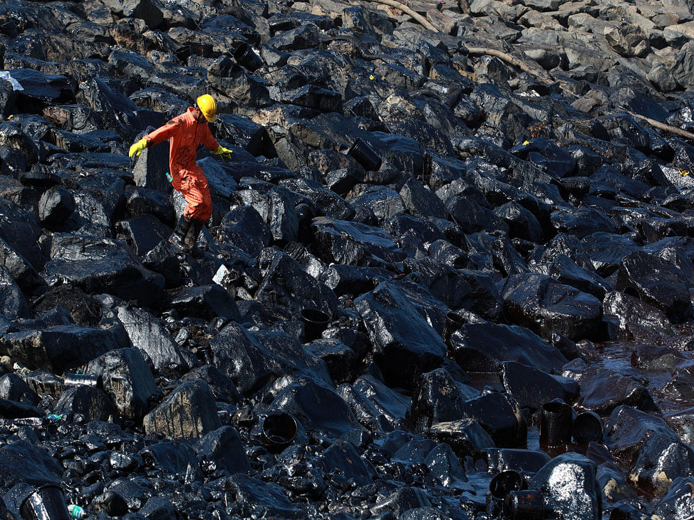 An emergency worker walks amidst oil deposits as he cleans oil from the shoreline of Ennore Port following a collision between two oil tankers, in Chennai. Reuters photo