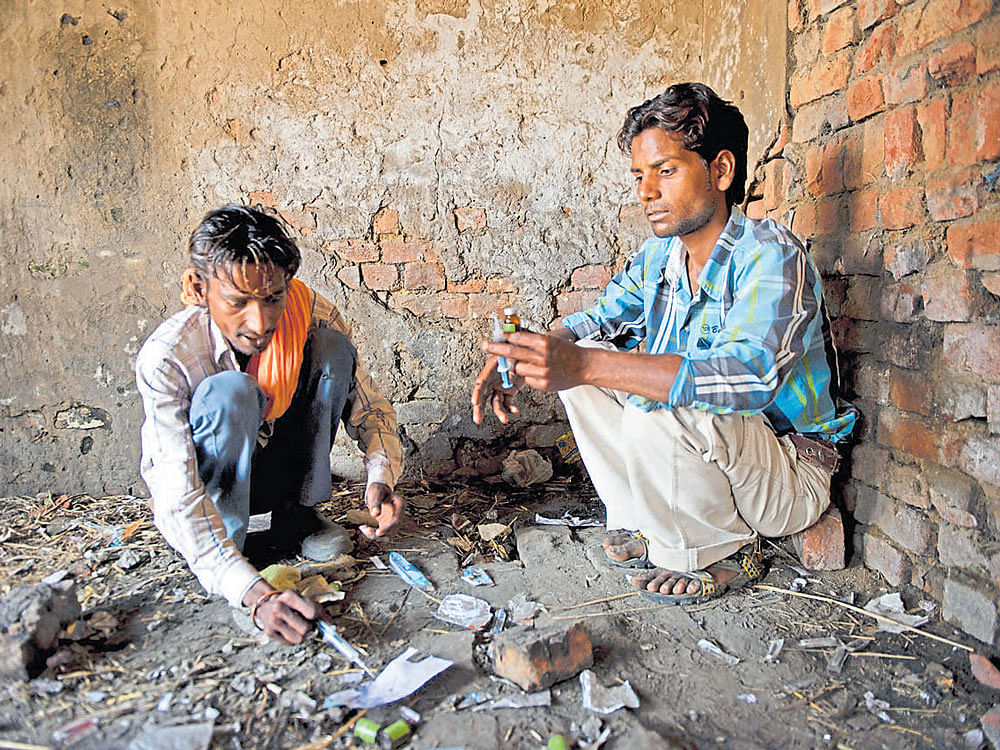 On a high: Pargat Singh (left) a long-time drug user and his friend prepare to inject drugs at an abandoned building in Punjab. The state has a large and growing drug problem that many health officials complain that the government is not checking. nyt