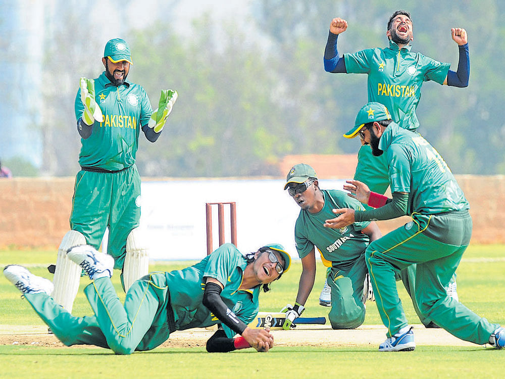 acrobatic Pakistan's Mattiullah (on the ground) takes a catch to dismiss South Africa's  Kenneth Mabela as team-mates celebrate on Monday. DH photo/ srikanta sharma R