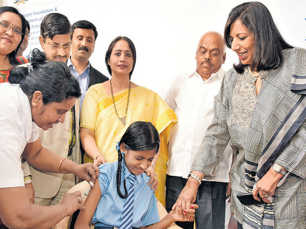 A nurse vaccinates a schoolgirl against measles and rubella at the inauguration of an eLAJ smart clinic in Bengaluru on Tuesday. (From right) Biocon chairperson Kiran Mazumdar-Shaw, Health and Family Welfare Minister K R Ramesh  Kumar and the department's Principal Secretary Shalini  Rajneesh look on. DH PHOTO