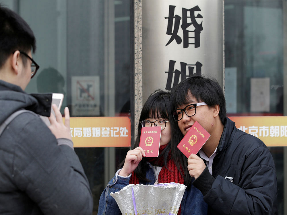 A new couple holding marriage certificates poses for a photo outside a registry office of marriage on Valentine's Day in Beijing, China. Reuters Photo.