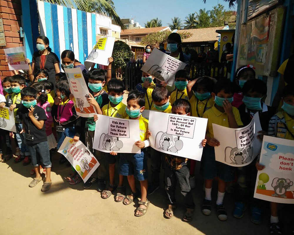 Residents and children from Nallurhalli hold placards to protest against the neglect of their area. DH Photo