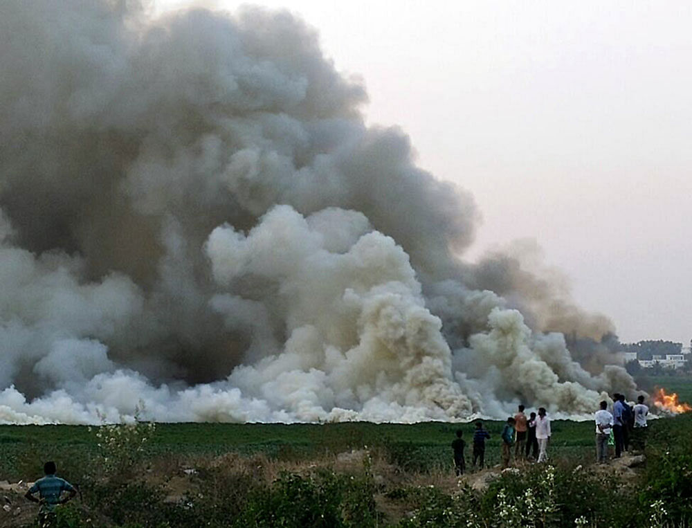 Thick smoke emanates from a pile of waste dumped in the Bellandur lake area on Thursday.  DH Photo