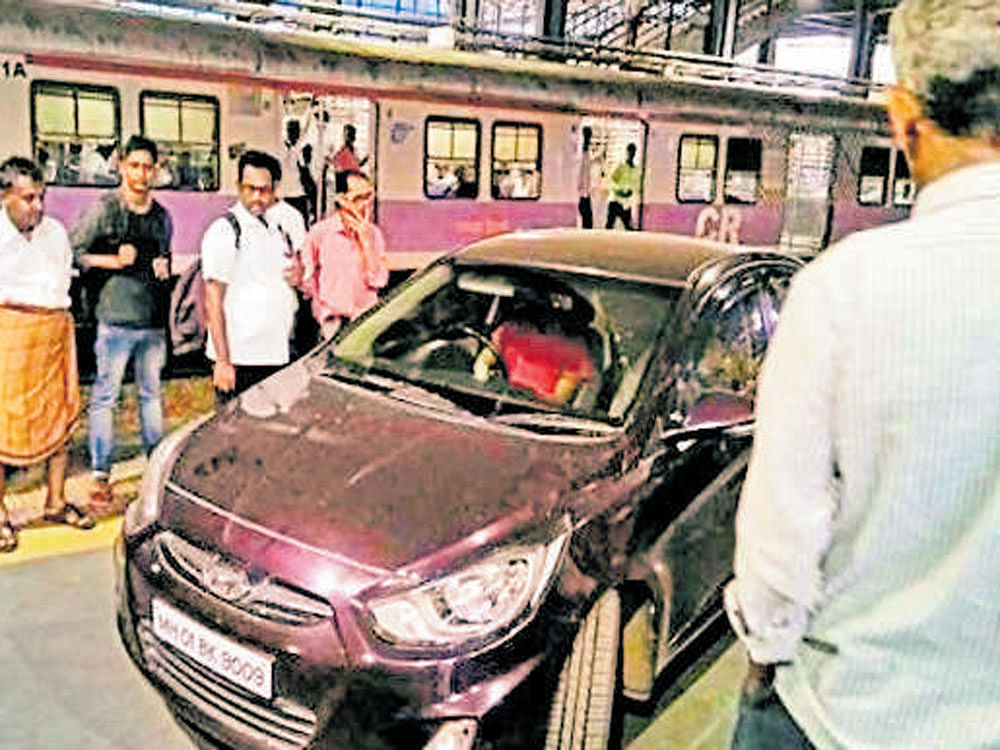 Commuters look at the car which was driven on to the platform by Harmeet Singh