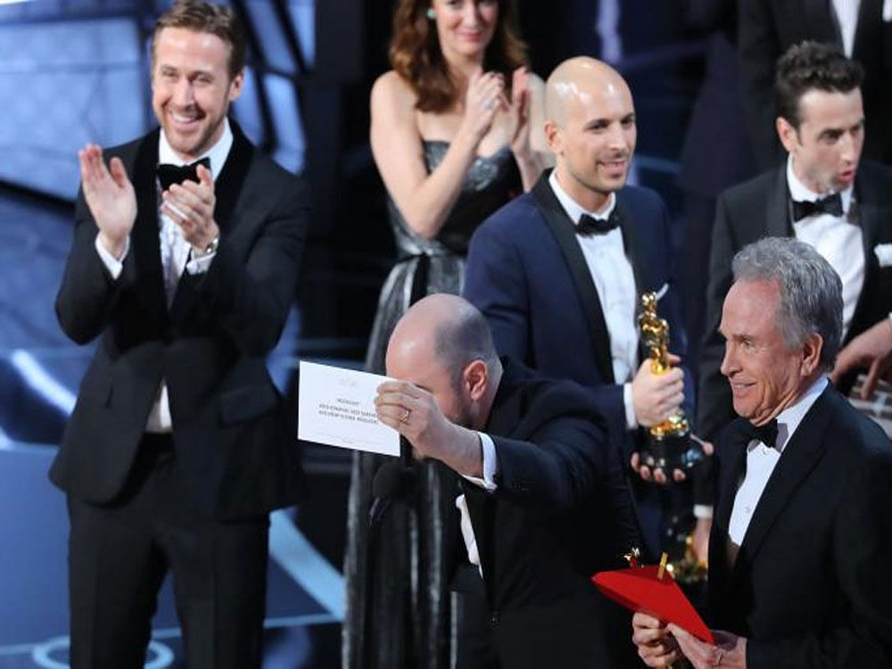 Producer Jordon Horowitz holds up the card for the Best Picture winner Moonlight. At left is Ryan Gosling and right is presenter Warren Beatty who mistakenly announced La La Land as the best picture winner. REUTERS