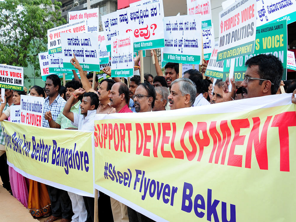 Members of 'Karnataka Abhivruddi Mattu Anustana Samiti' staging a protest demanding implementation of Elevated flyover or alternate traffic solutions to ease out traffic jam along bellary road, in front of Esteem Mall in Bengaluru on Sunday. DH photo