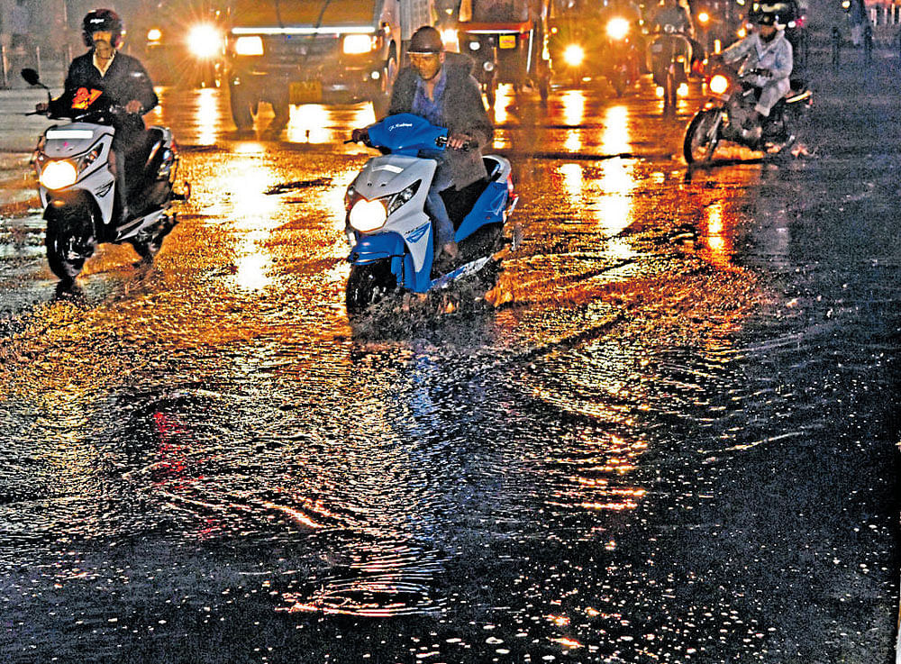 Motorists struggle to navigate on a waterlogged road near Anil Kumble Circle. DH Photo