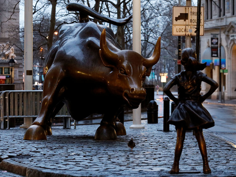 A statue of a girl facing the Wall St. Bull is seen, as part of a campaign by U.S. fund manager State Street to push companies to put women on their boards, in the financial district in New York, U.S., March 7, 2017. REUTERS