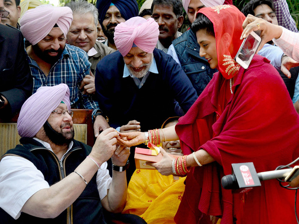 PPCC President Capt Amarinder Singh being offering sweets by his relatives during his press conference after the party's thumping win in state Assembly elections in Chandigarh on Saturday. PTI Photo