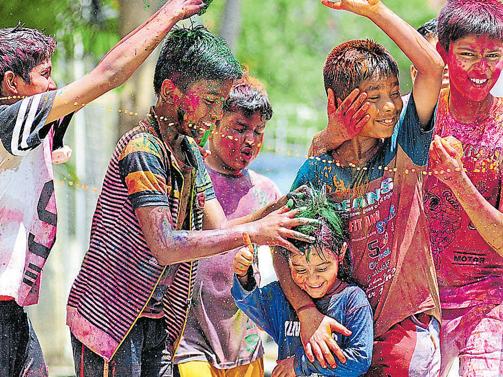 Children celebrate Holi with colours in Shantinagar on Sunday. dh photo