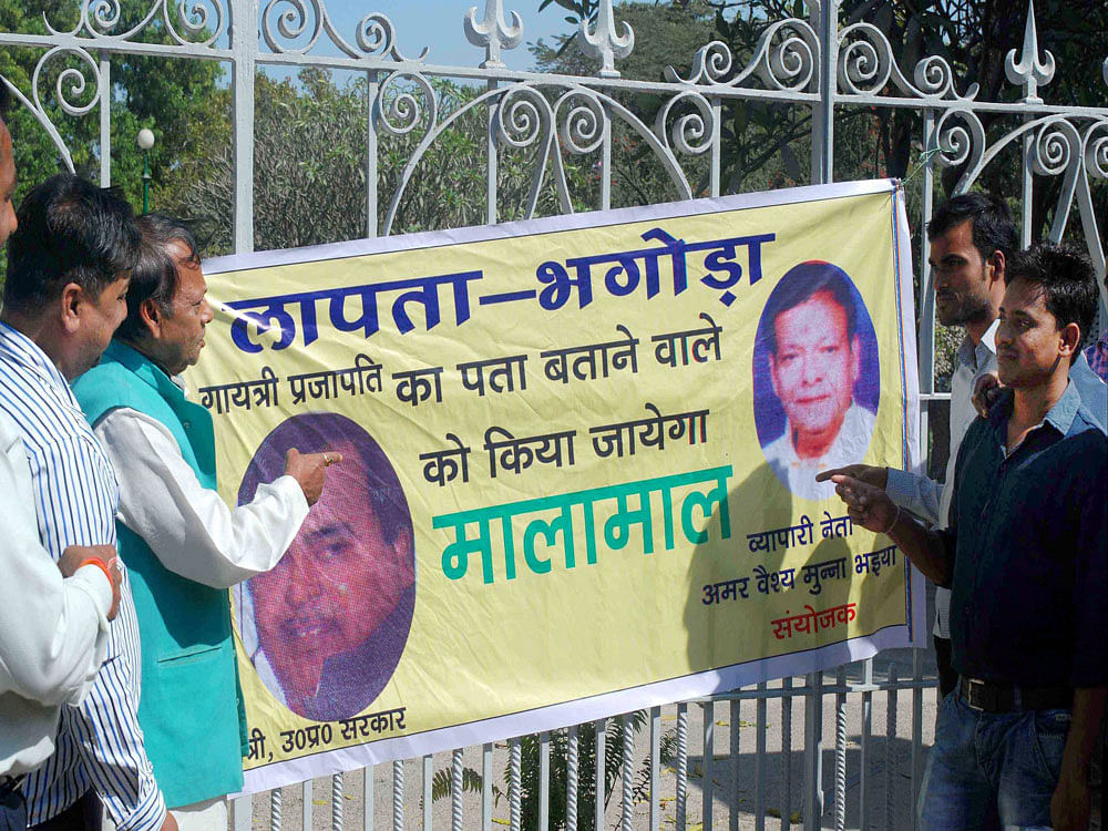 BJP workers put up a controversial poster promising reward for the information about cabinet minister Gayatri Prasad Prajapati, facing rape charges, at the entrance gate of historical Anand Bhawan in Allahabad on Monday. PTI Photo