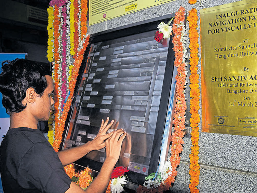 A visually challenged person reads a Braille map at the  KSR-city railway station on Tuesday. DH photo