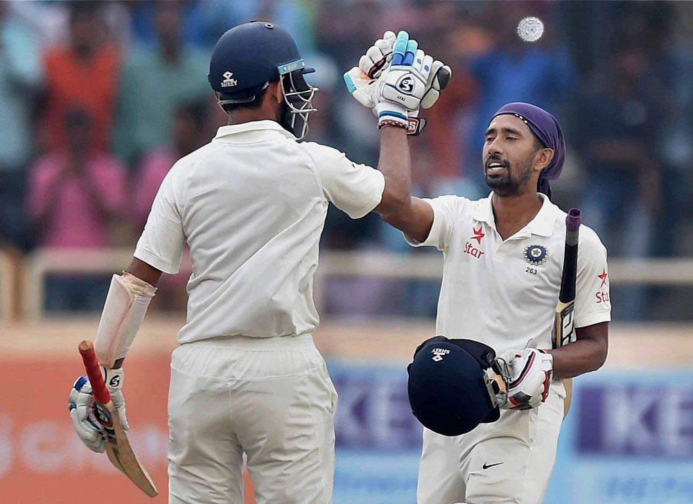 Indian batsman Cheteswar Pujara greets his teammate Wriddhiman Saha after he complete his century during 4th days play of 3rd test match against Australia in Ranchi on Sunday. PTI Photo