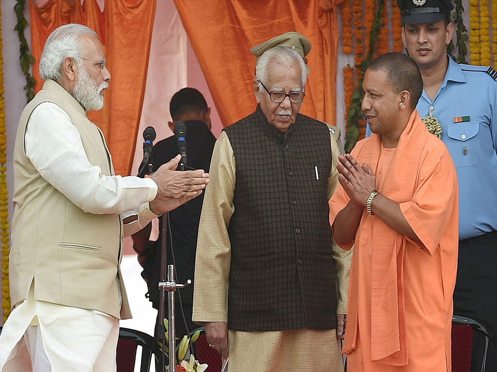 Prime Minister Narendra Modi congratulates newly sworn-in Chief Minister of Uttar Pradesh, Yogi Adityanath as Governor Ram Naik looks on, at the oath ceremony in Lucknow on Sunday. PTI Photo