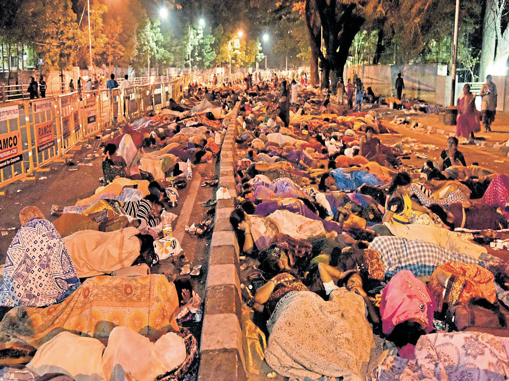 Anganwadi workers sleep on Sheshadri Road during their protest seeking higher wages on Monday night. dh photo by B K Janardhan