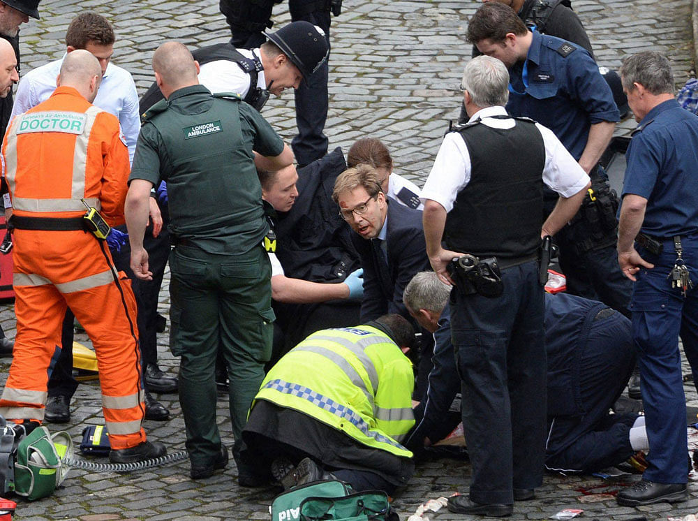 Conservative Member of Parliament Tobias Ellwood, centre, helps emergency services attend to an injured person outside the Houses of Parliament, London. AP/PTI