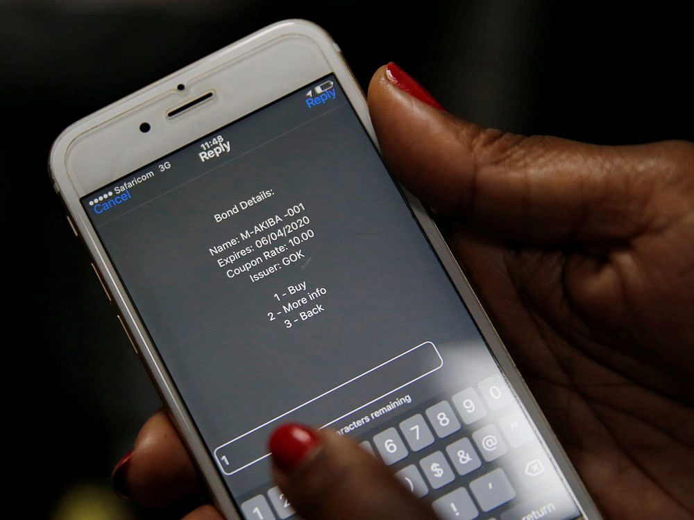 A delegate uses her cell phone to buy a M-Akiba bond during the launch of the first mobile-phone-based government bond at the Treasury building in Nairobi, Kenya. REUTERS Photo