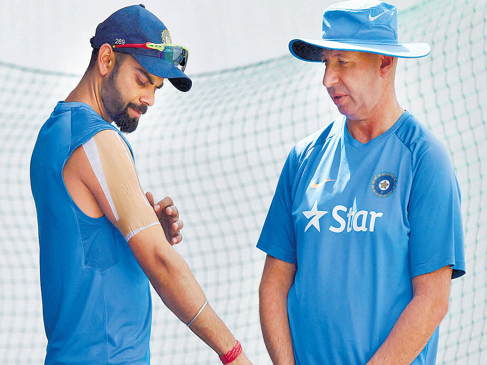 huge setback: Indian skipper Virat Kohli shows his injured shoulder to physio Patrick Farhart on Thursday. Kohli didn't bat  during Thursday's training session and there are concerns that he may not play the final Test at Dharamsala. PTI