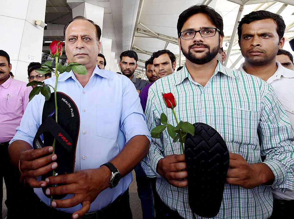 Aam Aadmi Sena activists hold roses and slippers as they protest against Shiv Sena MP Ravindra Gaikwad, at IGI Airport in New Delhi on Friday. PTI