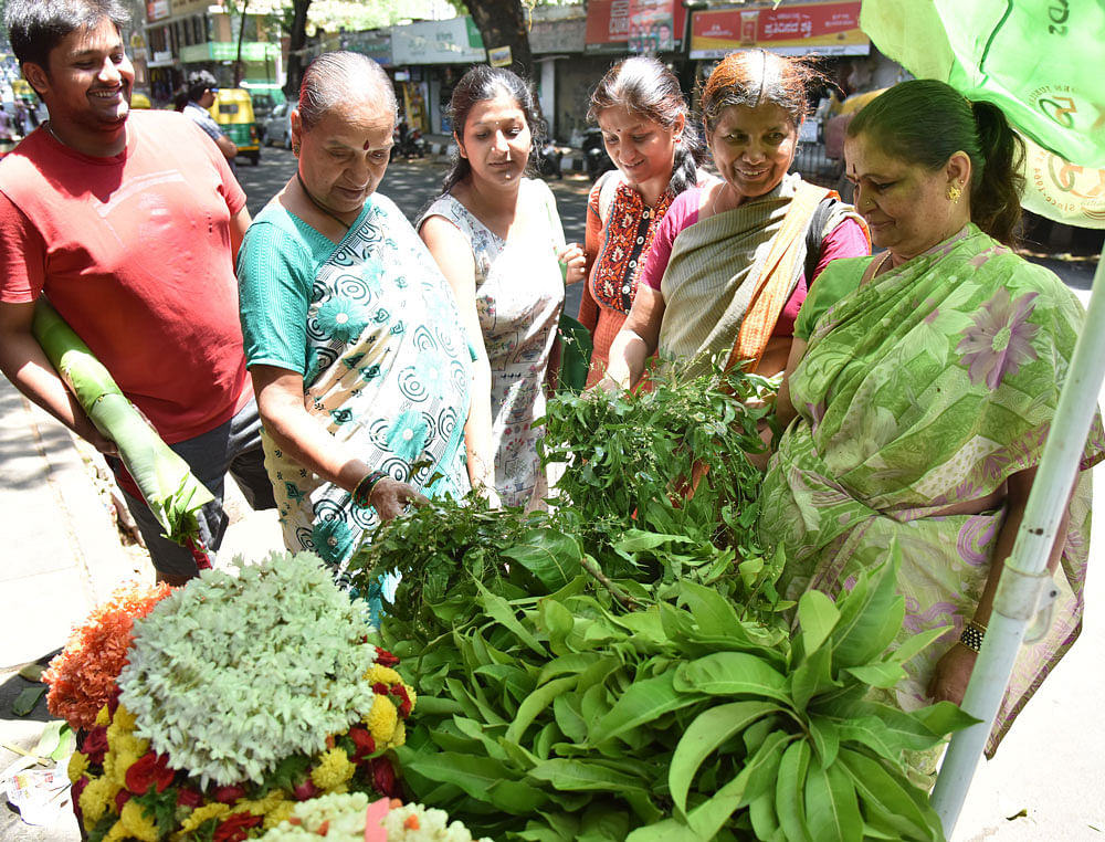 Excited: Customers at Malleswaram Market choosing mango and neem leaves. DH photo