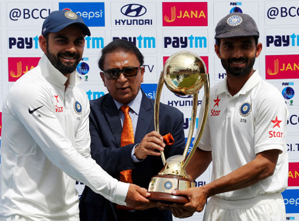 Virat Kohli (L) and Ajinkya Rahane (R) receive the trophy from the former Indian cricket player Sunil Gavaskar after winning the series. REUTERS