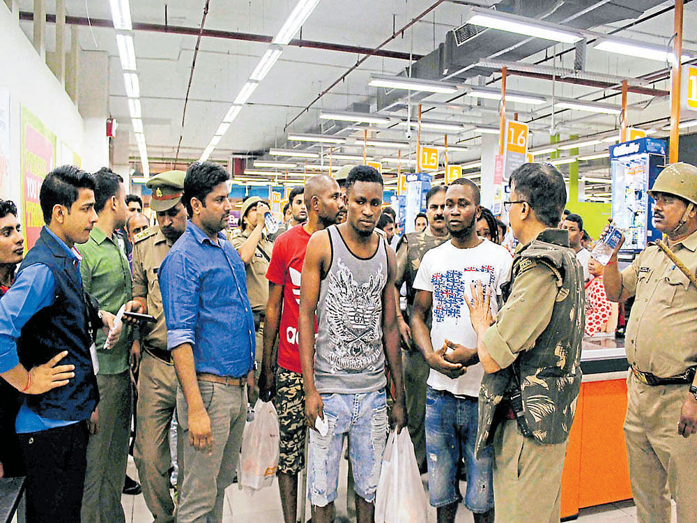 Police and onlookers surround African nationals at a shopping mall in Greater Noida on Monday.