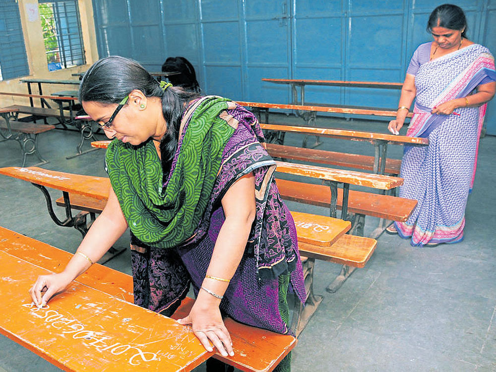 Teachers mark register numbers of SSLC&#8200;students on benches at Netaji Subhas Chandra Bose Government High School at Hombegowda Nagar in Bengaluru on Tuesday. The SSLC&#8200;examinations will start from on Thursday. DH photo