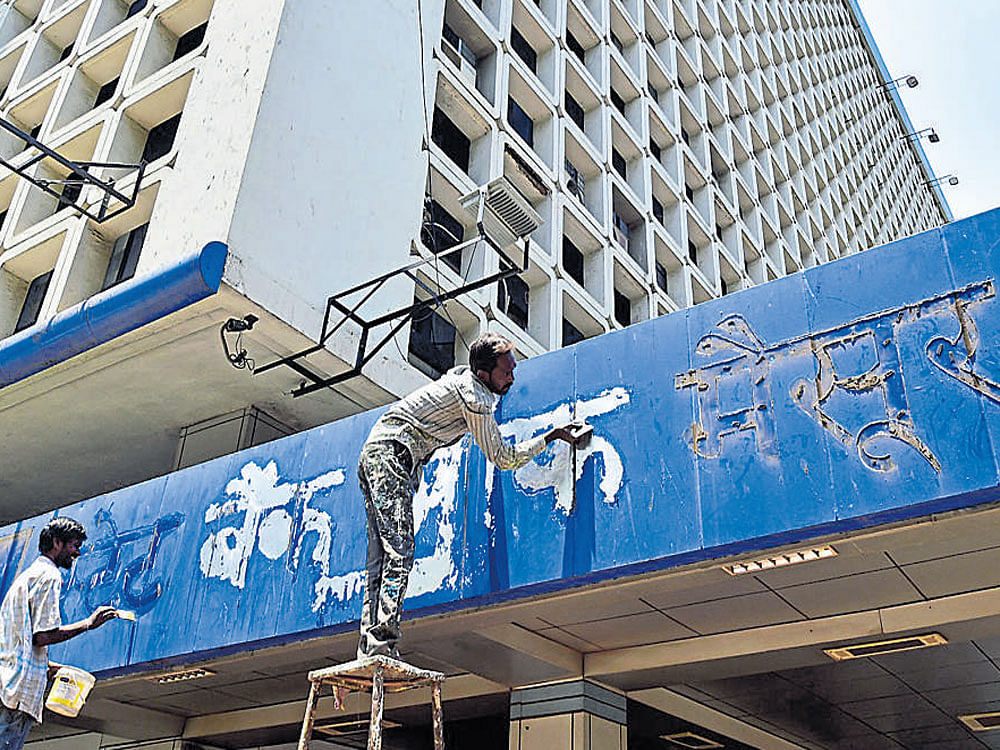 Workers remove the name board of State Bank of Mysore at the bank's head office on KG Road in Bengaluru on Thursday. dh Photo