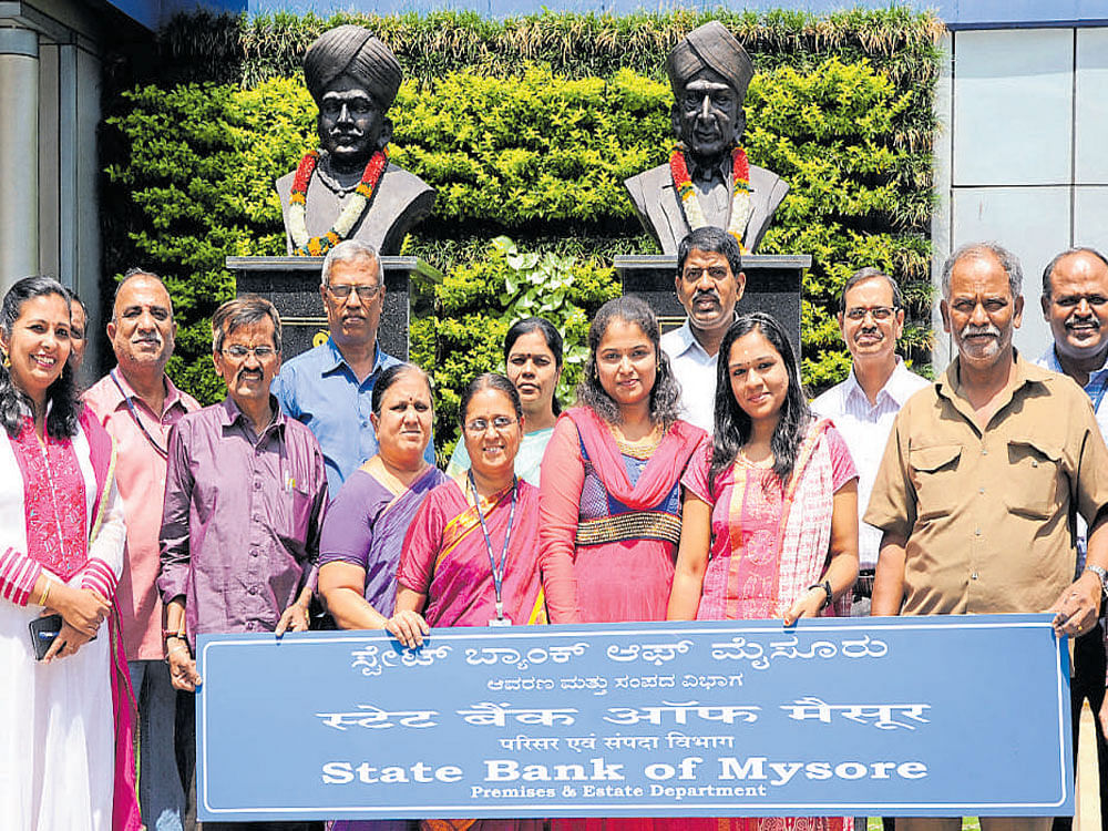 SBM employees pose for a photograph in front of the busts of Nalvadi Krishna Raja Wadiyar and Sir M Visvesvaraya at the head office of the bank on KG Road in Bengaluru on Thursday. DH Photo
