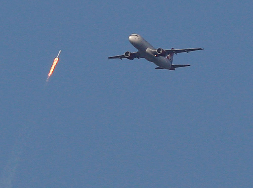 A recycled SpaceX Falcon 9 rocket soars toward space above a Virgin Airlines passenger jet, which had just departed Orlando International Airport, in Orlando, Florida, March 30, 2017. The launch marked the first time ever that a rocket was reused for spaceflight. REUTERS