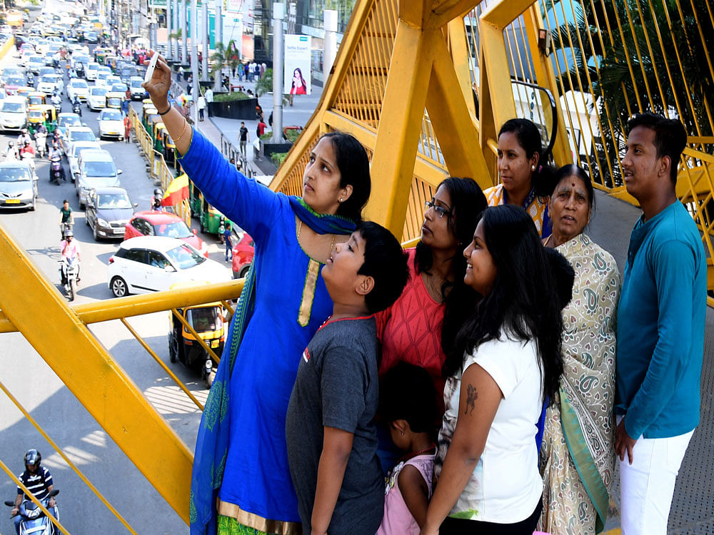 Pedestrians click a selfie on the skywalk, as a part of the selfie contest, conducted by the city traffic police to encourage people to use skywalks and create awareness. dh PHOTO