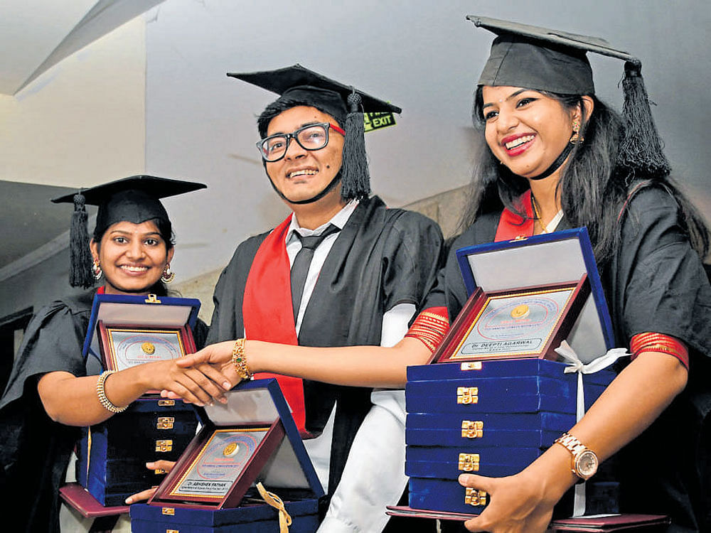 (Fromleft) Swathimutthu B N(five golds in BAMS), Abhishek Pathak (four in BDS) and Deepti Agarwal (five in MBBS) greet each other at the 19th annual convocation of Rajiv Gandhi University of Health Sciences (RGUHS) in Bengaluru on Thursday. DH PHOTO