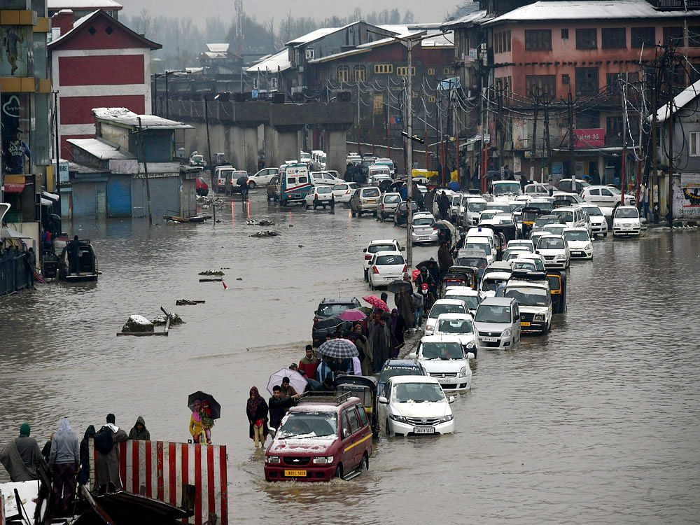 Vehicles make way through a waterlogged street following heavy rains in Srinagar on Thursday. Srinagar and other parts of Kashmir have been experiencing heavy rains and snowfall, a rare scene in the month of April, for the past three days, prompting authorities to announce flood alert in the valley besides closure of educational institutes. PTI Photo