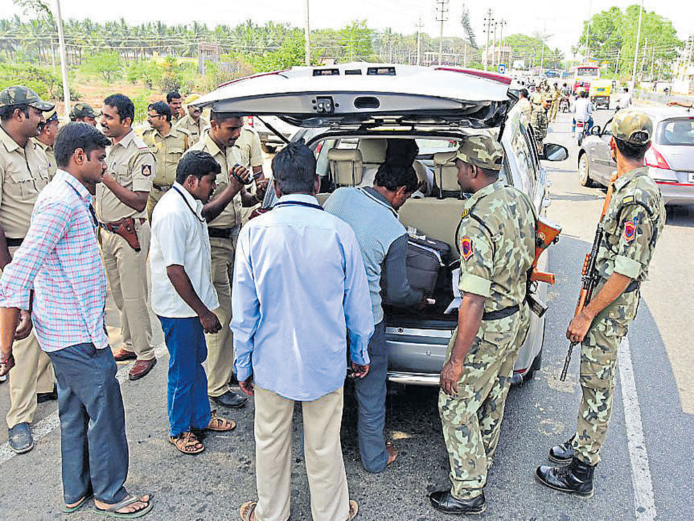 Security personnel deputed at a check-post inspect a vehicle in Nanjangud, Mysuru district, on Tuesday.&#8200;DH photo