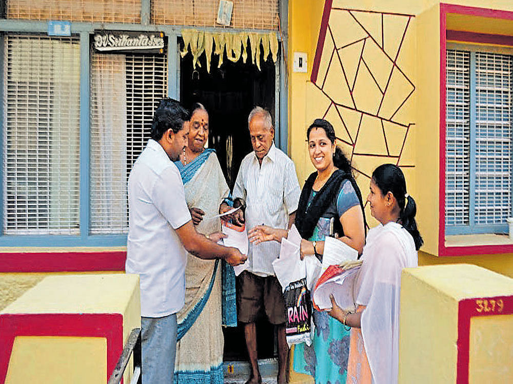 The workers of a political party hold a door-to-door campaign in favour of their candidate in Nanjangud on Saturday. DH photo