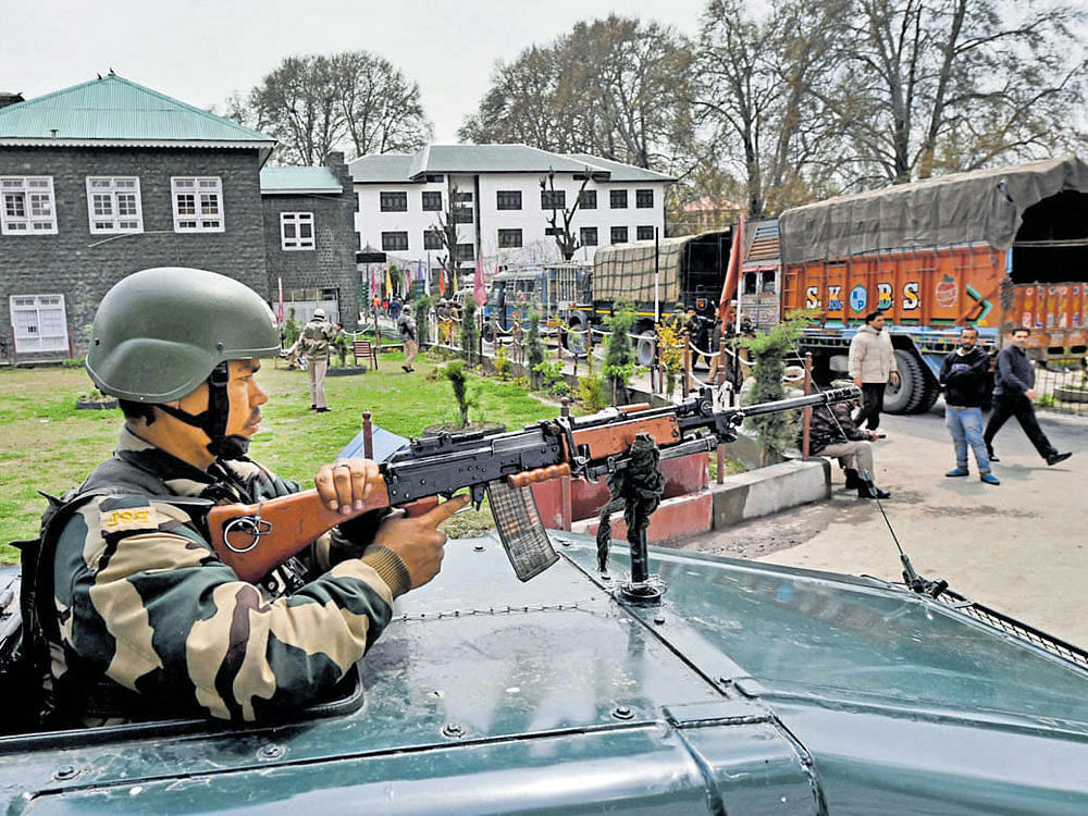 A security jawan stands guard atop an armoured vehicle outside an EVM distribution centre set up in a school, before elections to Srinagar Lok Sabha seat, on Saturday. PTI