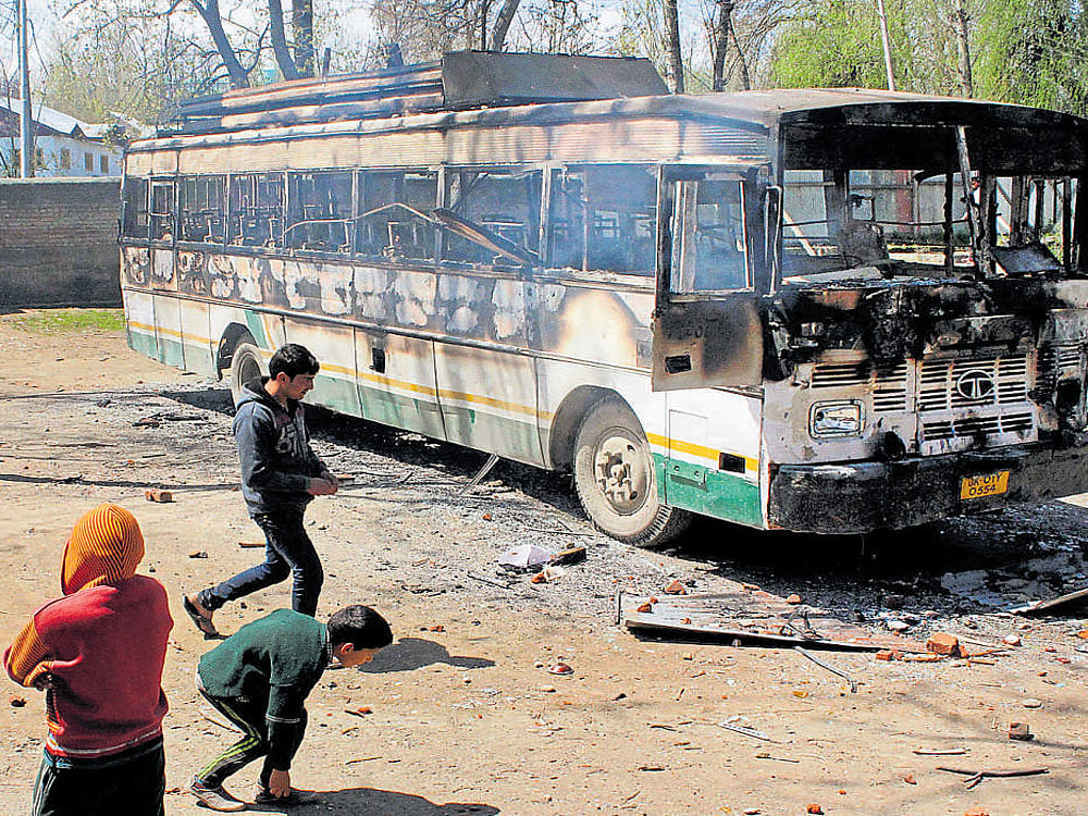 Protesters throwing stones at a bus after they attacked a polling station at Kanihama in Srinagar on Sunday. The bus meant for the polling staff was torched by the agitators. PTI