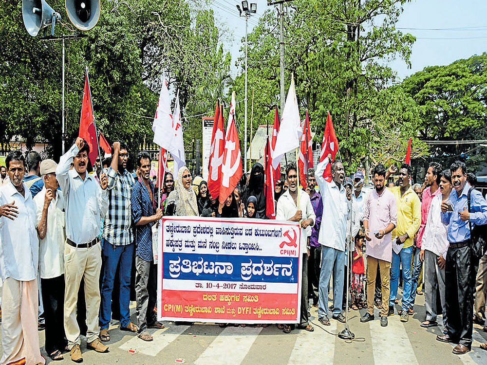 The residents of Thannirbavi stage a protest demanding title deeds and door numbers for their houses, in front of the DC's office in Mangaluru on Monday.
