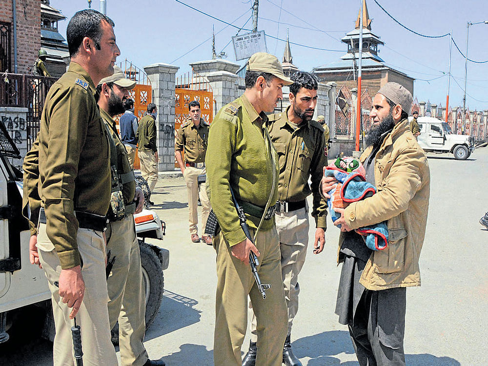 A man with a baby is questioned by security personnel on Monday after restrictions were imposed in  Srinagar following a strike call given by the joint Hurriyat leadership in protest against the killing of eight civilians in Sunday's poll-related violence. PTI