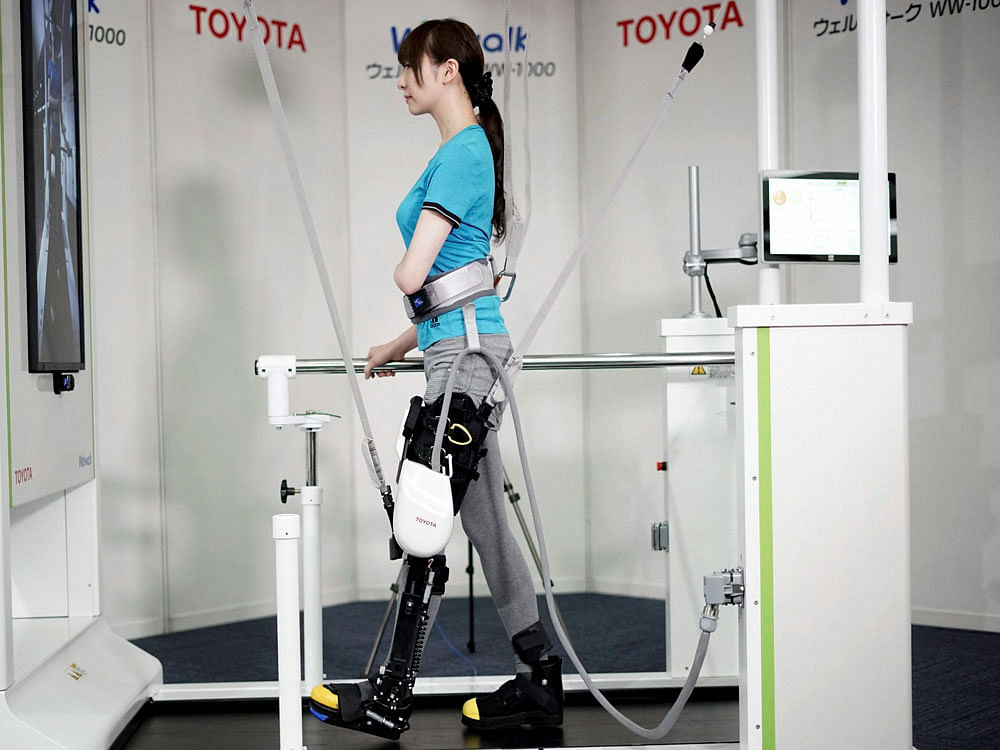 A model demonstrates the Welwalk WW 1000, a wearable robotic leg brace designed to help partially paralyzed people walk at the main system with treadmill and monitor, at Toyota Motor Corp's head office in Tokyo, Wednesday, April 12, 2017. Press Trust of India photo