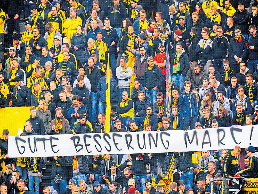 we are with you: Borussia Dortmund fans hold a banner which reads "Get well Marc" ahead of their game against Monaco on Wednesday. The game was postponed by a day after an explosion rocked the team bus on Tuesday that injured player Marc Bartra. RIGHT: A Monaco supporter says thank you to Dortmund for offering them accommodation. AFP