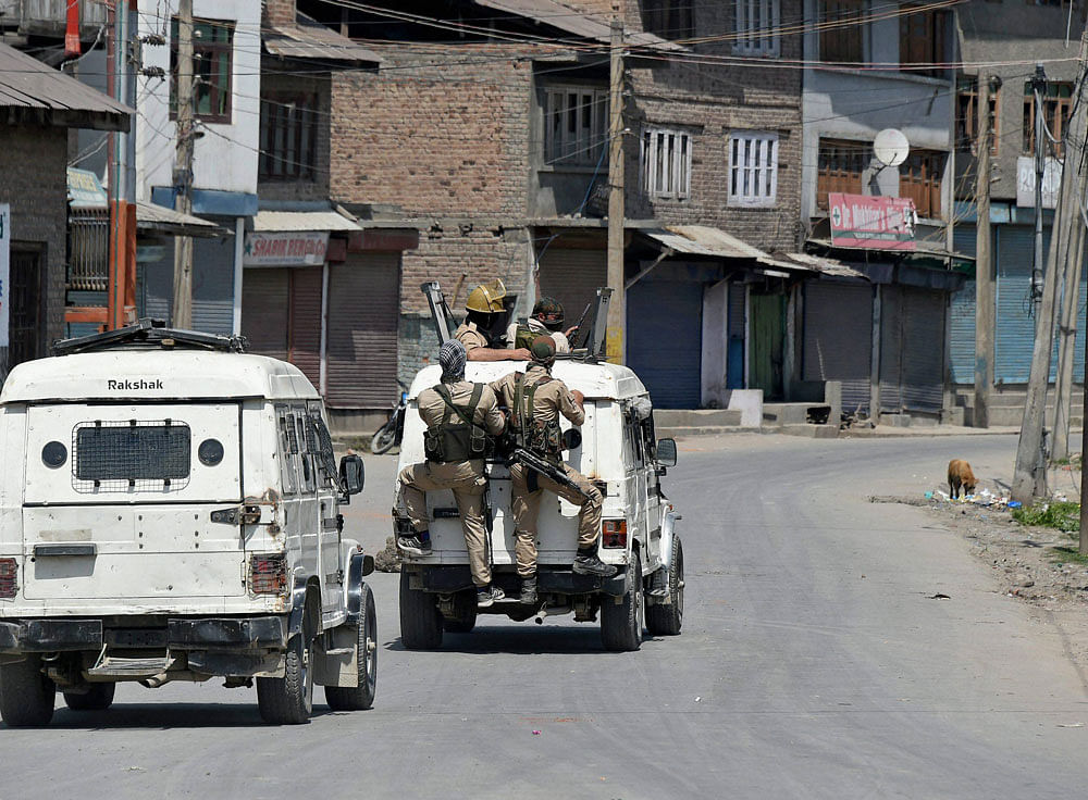 Policemen in vehicles patrolling a street during restrictions imposed by the goverment authorties and strike call given by Hurriyat Confrence following the killing of a youth, in Batamaloo area of Srinagar on Sunday. PTI Photo