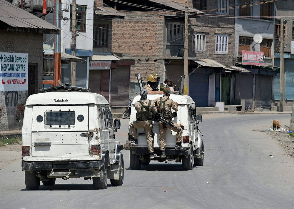 Policemen in vehicles patrolling a street during restrictions imposed by the goverment authorties and strike call given by Hurriyat Confrence following the killing of a youth, in Batamaloo area of Srinagar on Sunday. PTI Photo