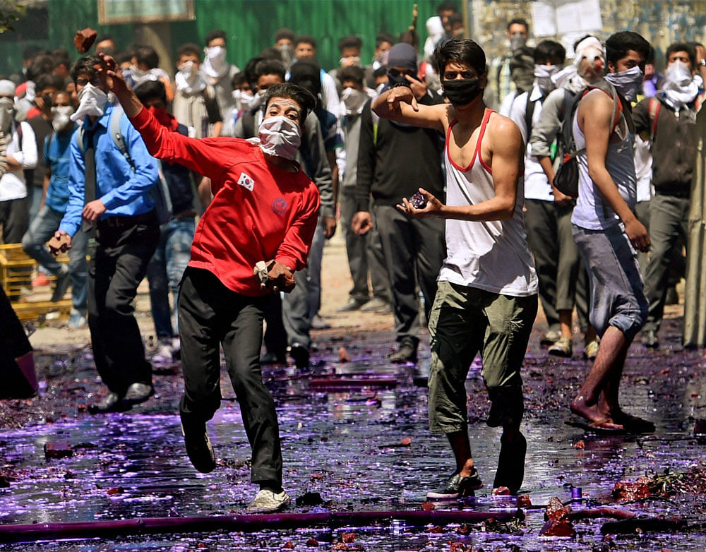 Students pelt stones at security forces personnel during a clash in Srinagar on Monday. PTI Photo