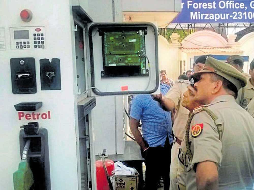 Police officers check a petrol pump machine in Mirzapur on Monday. Some petrol pumps were found using chips to cheat the customers. PTI