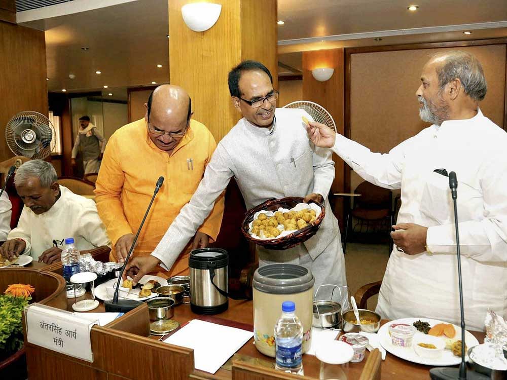 Madhya Pradesh Chief Minister Shivraj Singh Chouhan along with his cabinet colleagues sharing meals from the tiffins brought by other ministers after the cabinet meeting at State Mantralaya in Bhopal. PTI Photo