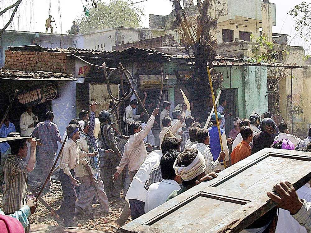 This file photograph taken on March 2, 2002, shows a mob of Indian Hindus armed with swords as they run down a street in the Bapunagar Area of Ahmedabad.  PTI