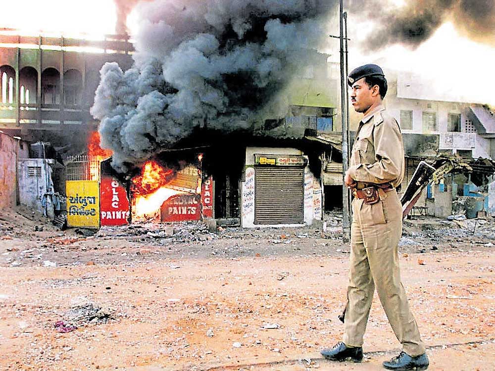 This photo taken on March 1, 2002, shows a policeman as he walks in front of a row of burning shops in Ahmedabad. afP
